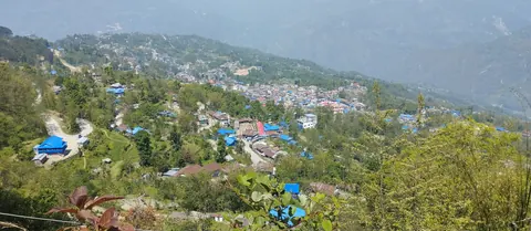 Taplejung bazaar spread across the hillside, seen from the trail above town