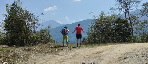 Two of our trekkers on a dirt road looking out over the forested hills on the walk out