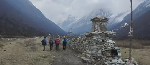 Trekkers passing a long mani wall on the way out of Samagaon
