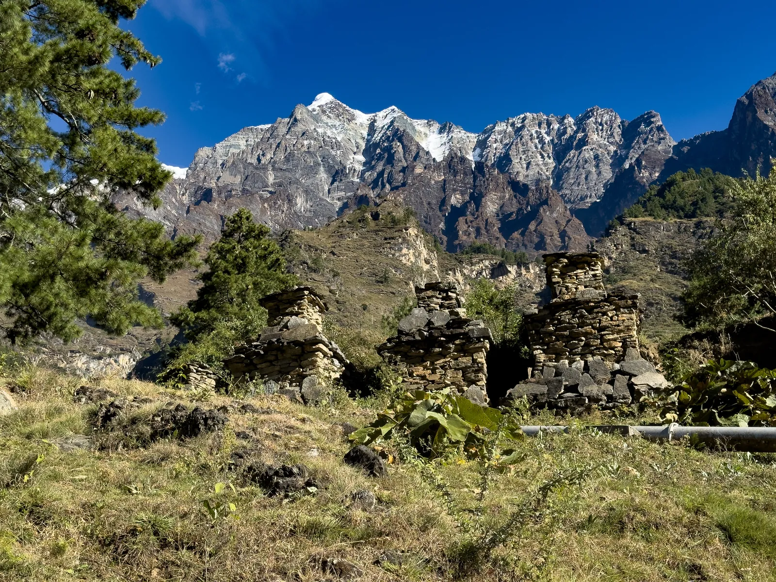 Weathered stone chortens in a meadow below jagged snow-streaked peaks