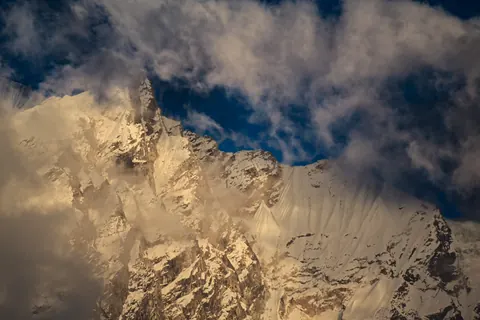 A snow face lit gold through breaking cloud