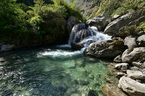 Clear green water in a rock pool below a small waterfall
