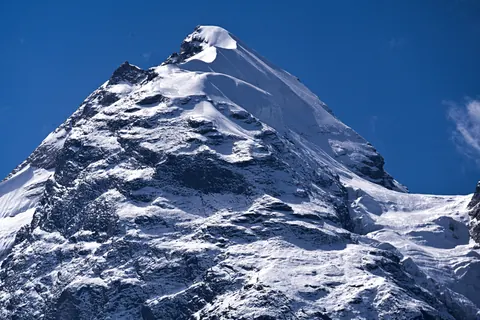 A pyramid-shaped snow peak against a blue sky