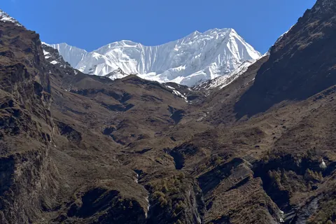 A brown, steep-sided valley with a white snow peak at its head