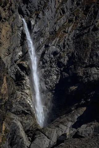 A thin waterfall falling down a dark rock wall in the gorge