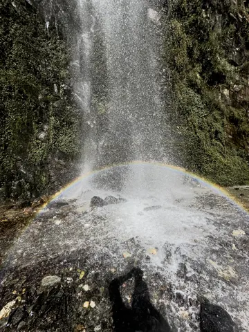 A rainbow forming in the spray at the base of a waterfall